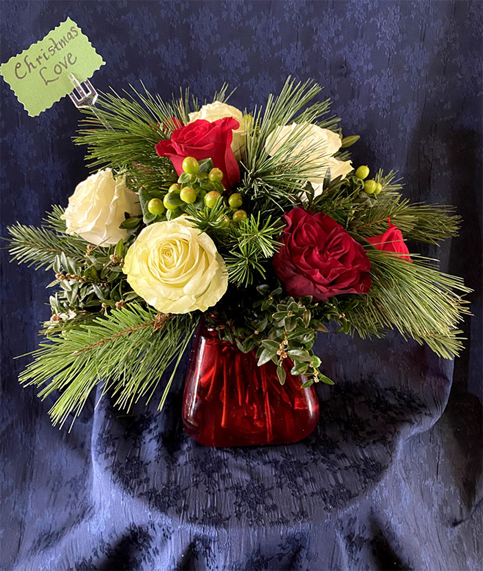 Christmas Love $85 Red glass pyramid vase, seasonal greens of fir and boxwood, dozen mixed red and white roses, green hypericum berries.